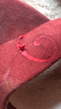 a close up of a red shoe with a red stitch on it