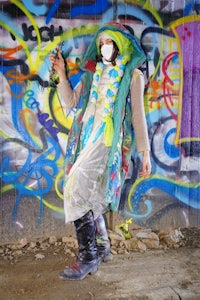 a person wearing a hat and a scarf laying on a graffiti covered wall